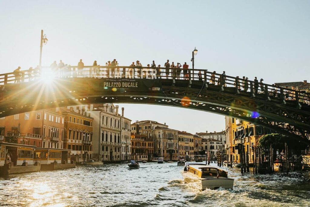 ludzie stojący na moście nad rzeką w słoneczny dzień